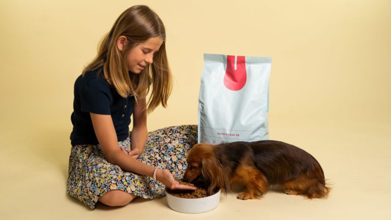 pige giver foder til hund